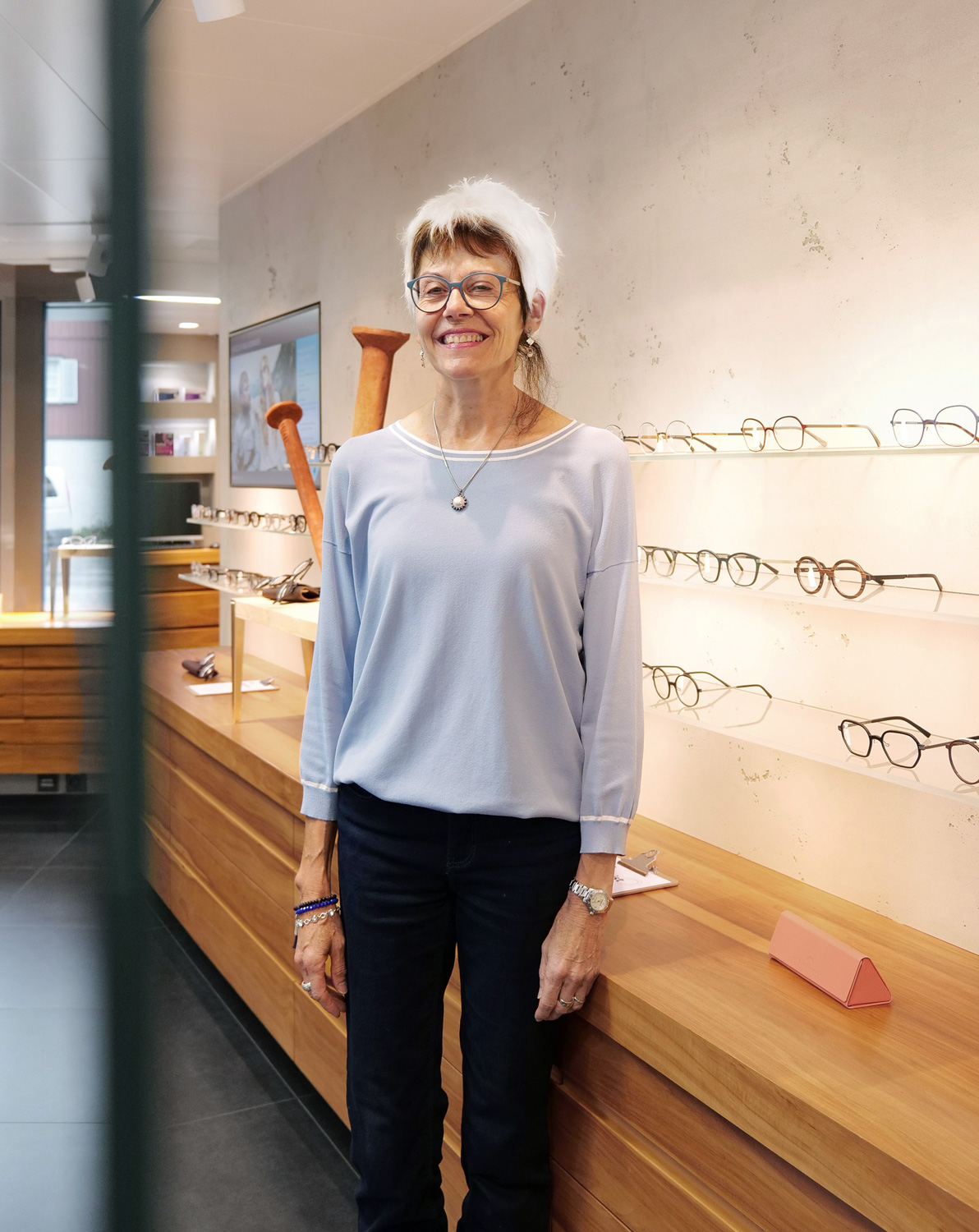 Eine Beraterin mit einer Brille vor einem Brillenregal